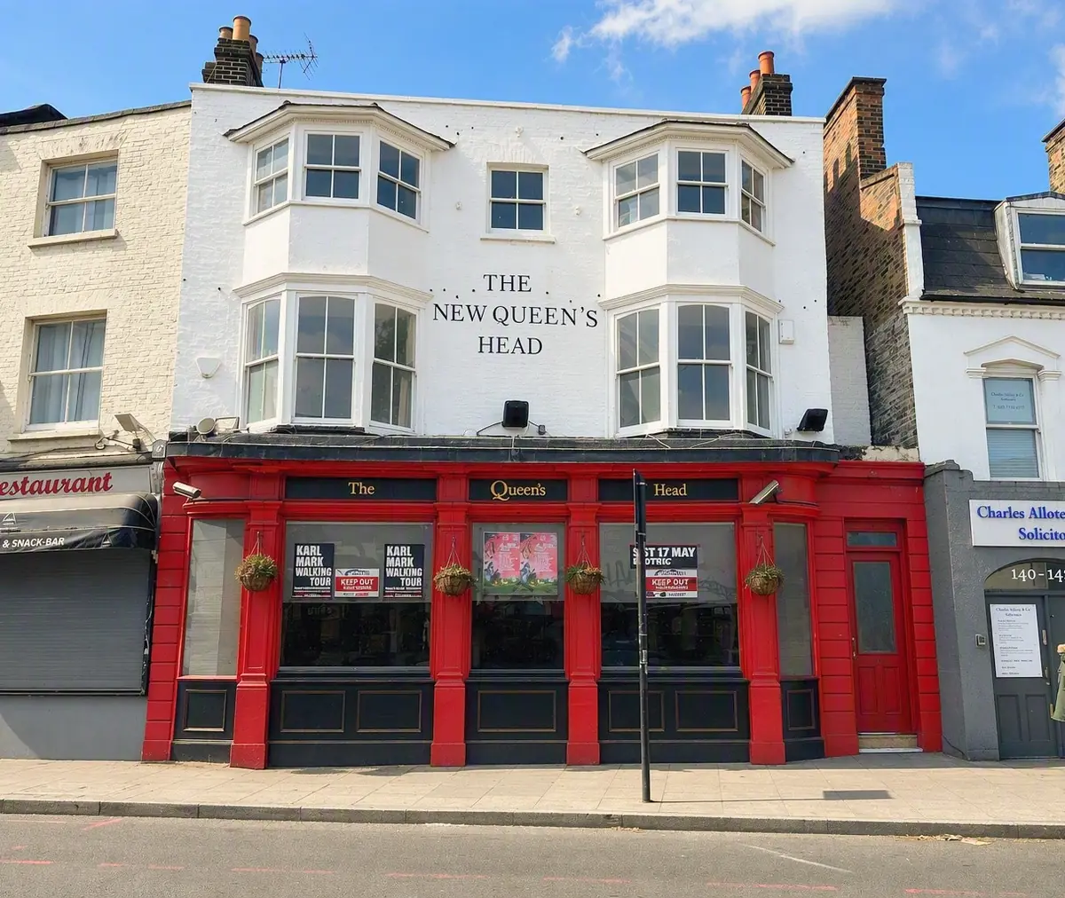 A public house with a white-painted upper floor, canted bay sash windows over two storeys above a painted timber shopfront